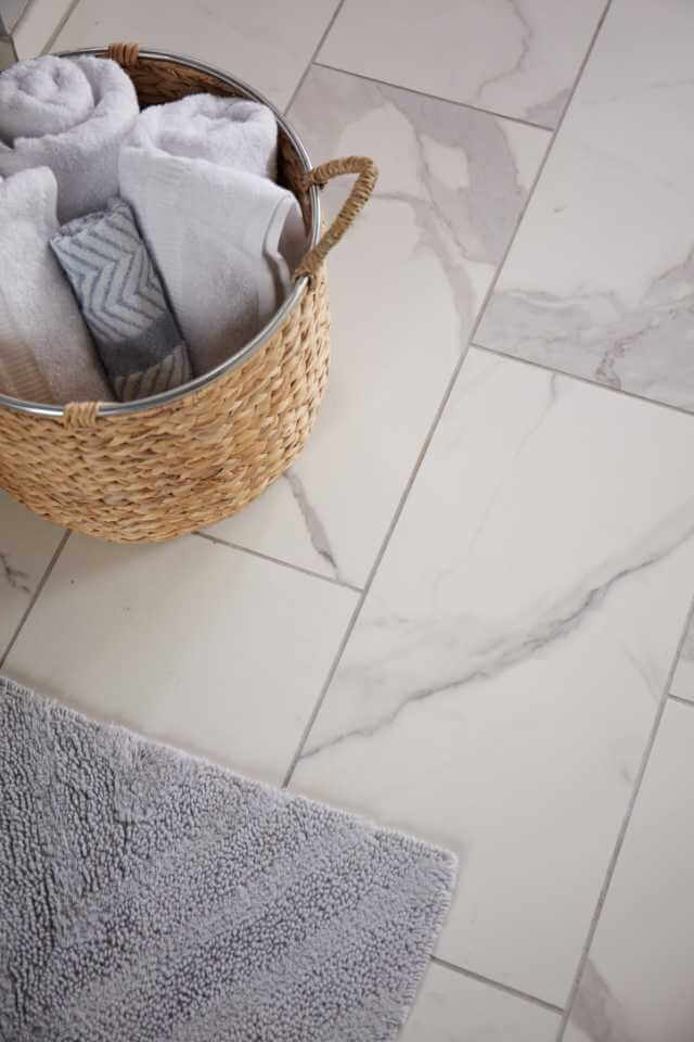 A basket with towels on the white tile floor